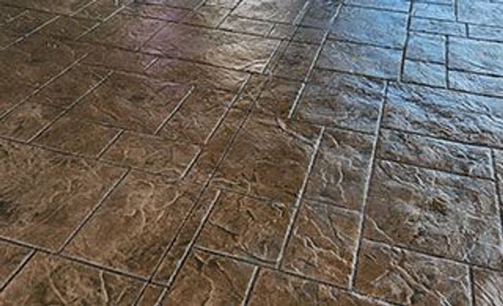 Stamped concrete flooring with a textured brown finish, showcasing detailed design patterns.
