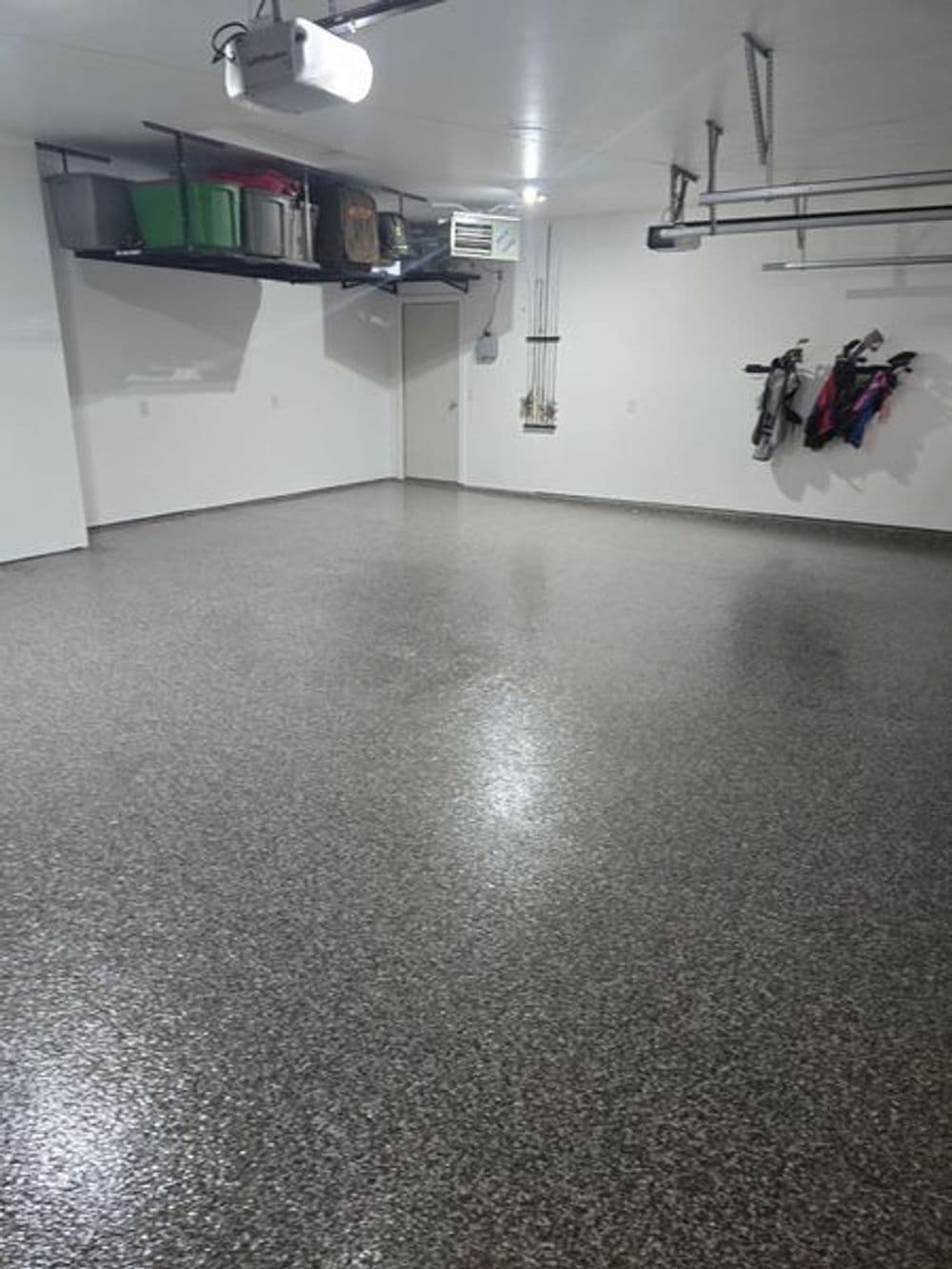 Spacious, clean garage with glossy floor and organized storage above.