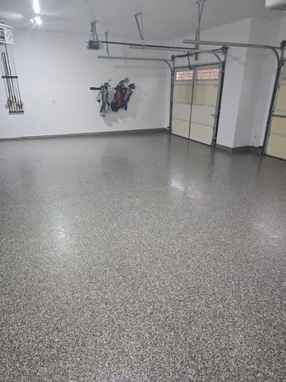 Spacious, clean garage with epoxy flooring and organized tools on the wall.