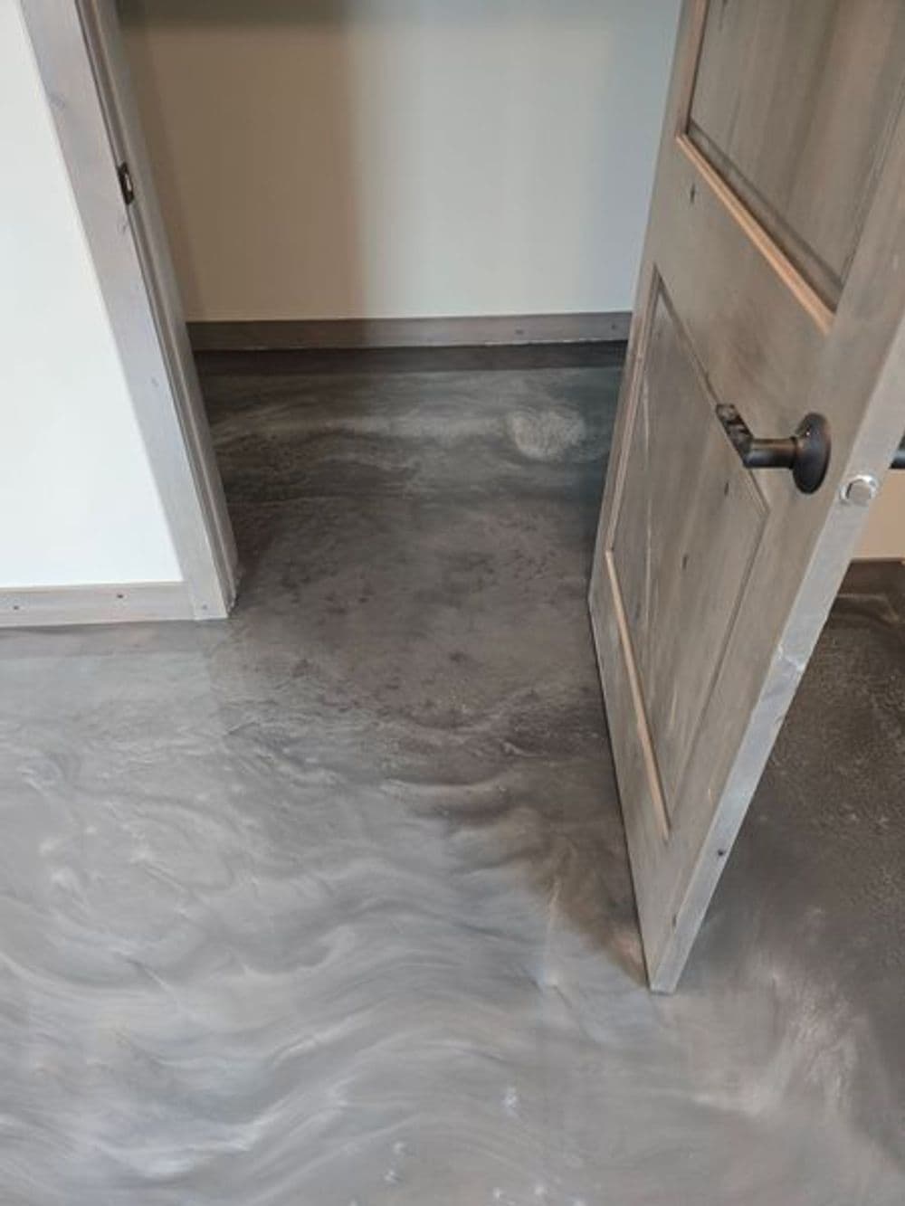 Modern gray epoxy flooring leading to an open door in a sleek interior space.