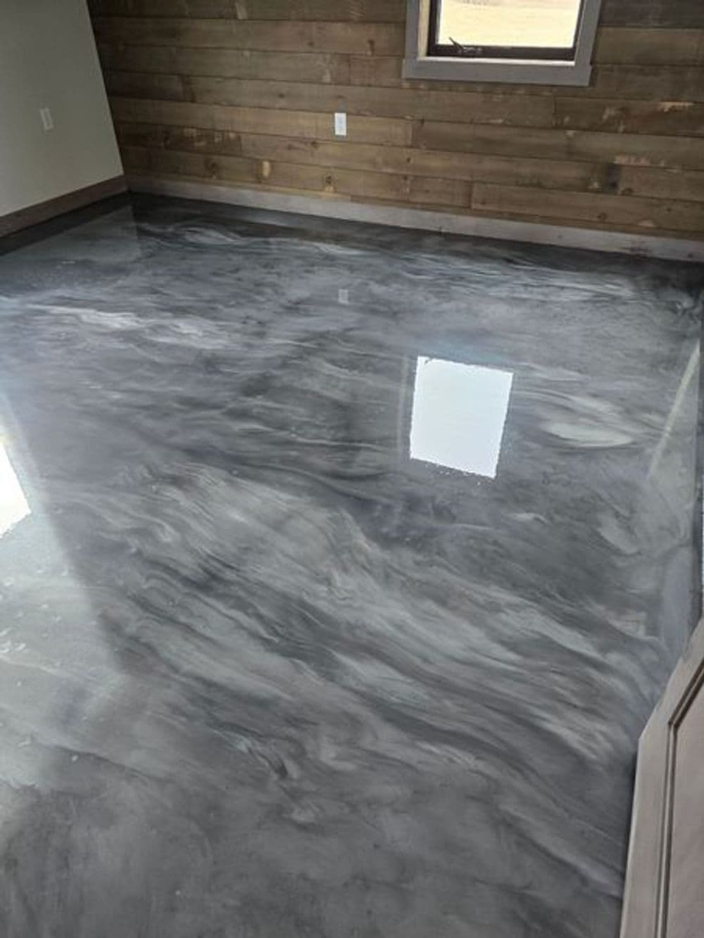 Glossy gray marble epoxy floor in a modern room with wooden wall paneling.