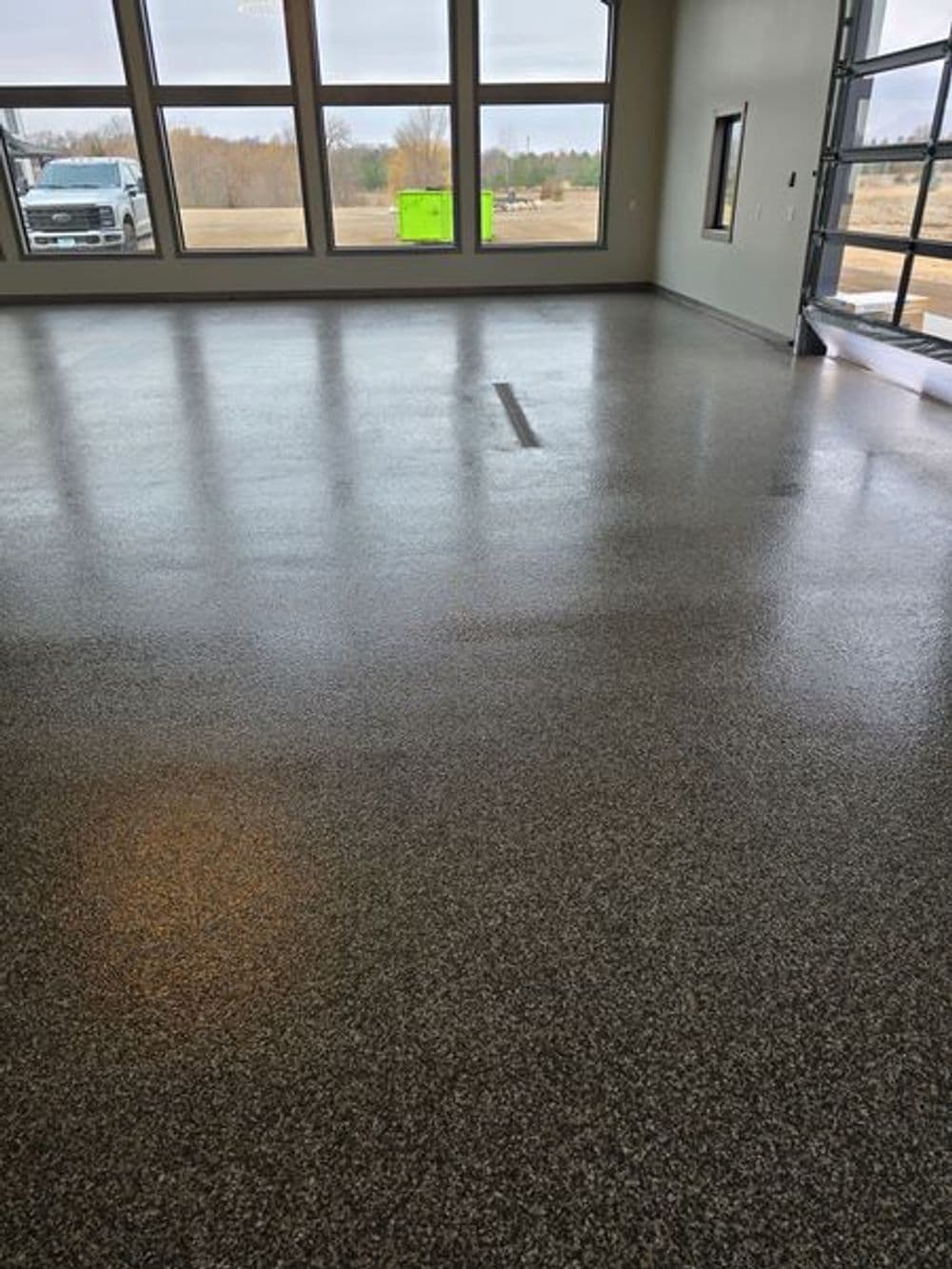 Polished epoxy floor in a spacious room with large windows and outdoor view.