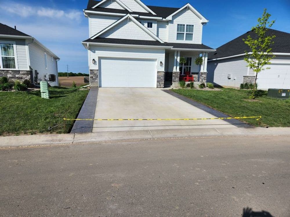 Newly built house with a spacious driveway and caution tape in front on a sunny day.