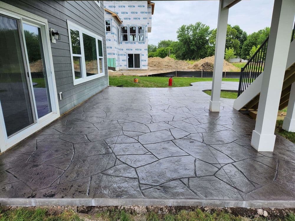 Textured stamped concrete patio with a view of a new construction house in background.