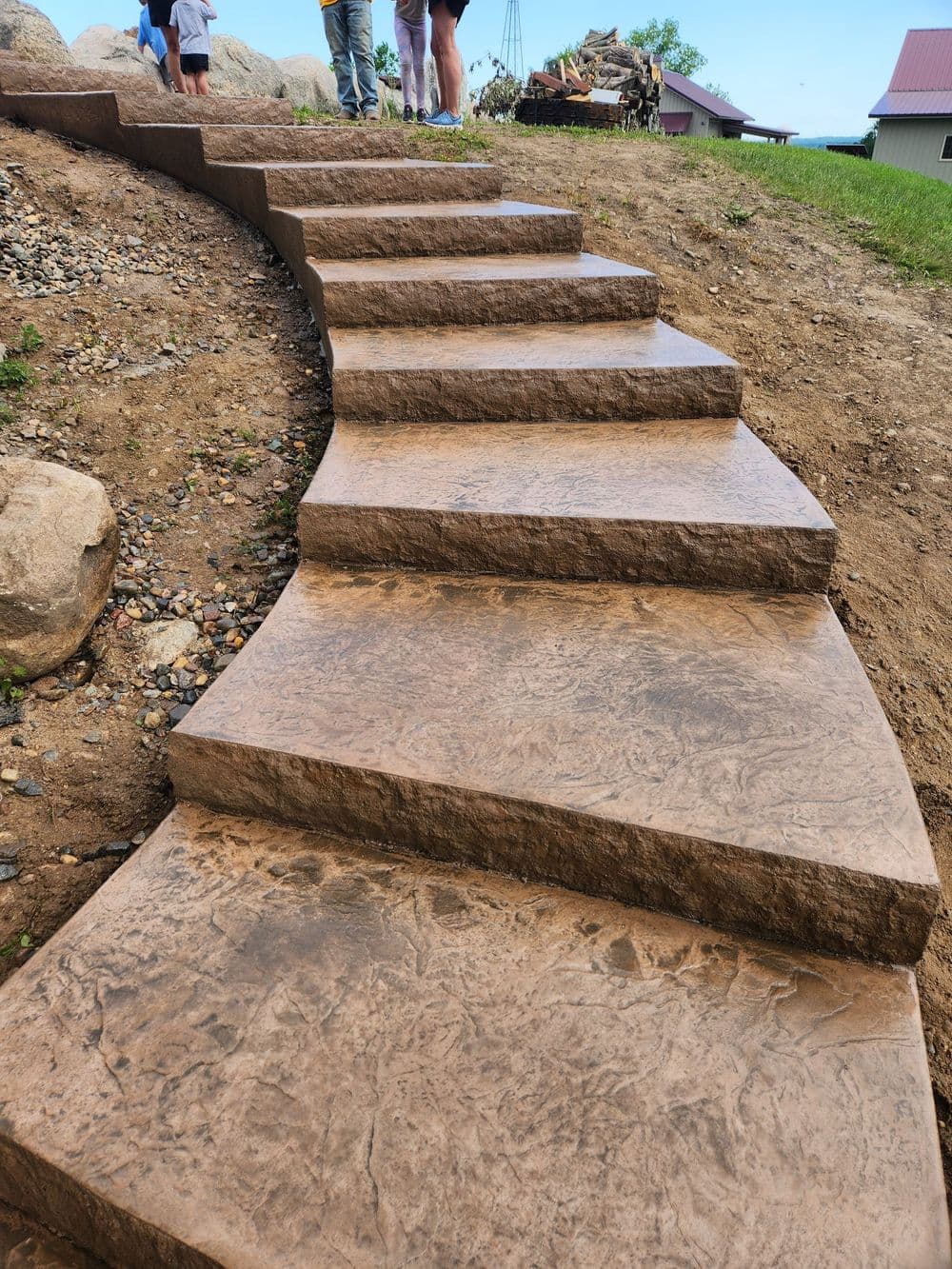 Curved stone steps leading up a hill with people in the background on a sunny day.