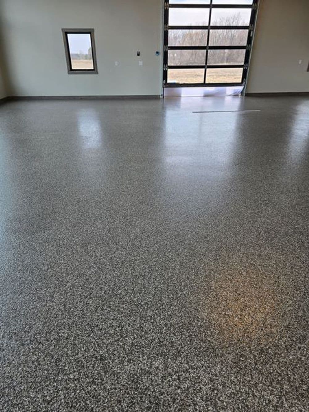 Polished concrete floor in a spacious garage with large windows and a garage door.