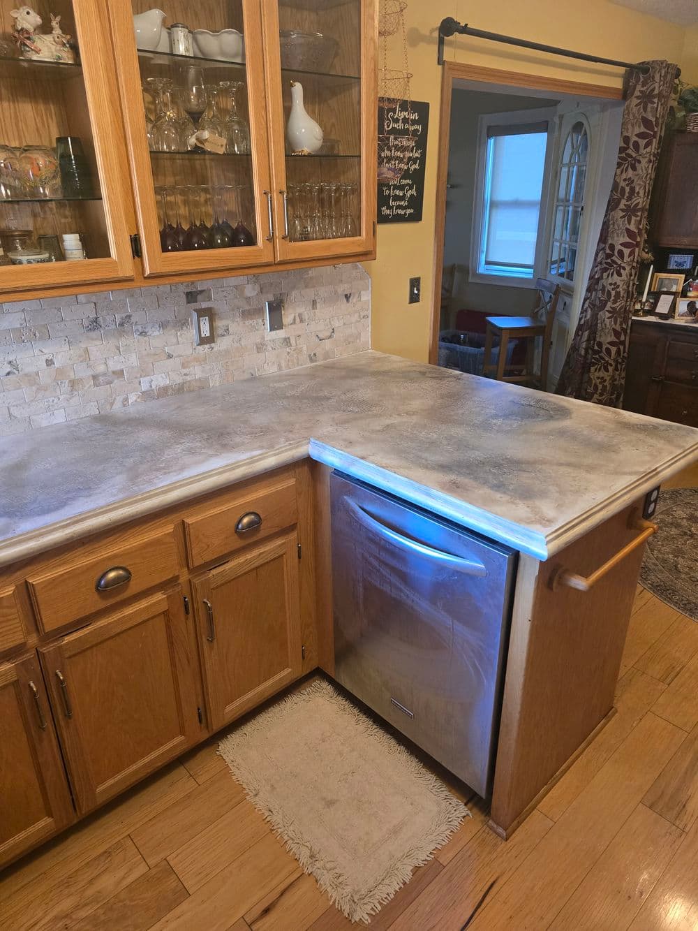 Modern kitchen with wooden cabinets, stone backsplash, and stainless steel dishwasher.