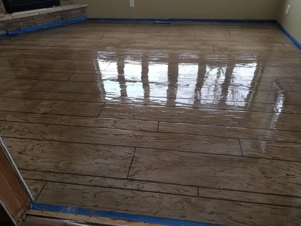 Shiny stained wood-look tile floor with blue painter's tape along the edges.